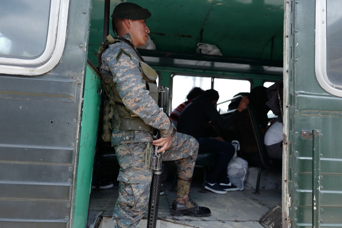 Un soldado vigila un autobús que transporta a inmigrantes detenidos en Estados Unidos a su regreso a Guatemala.