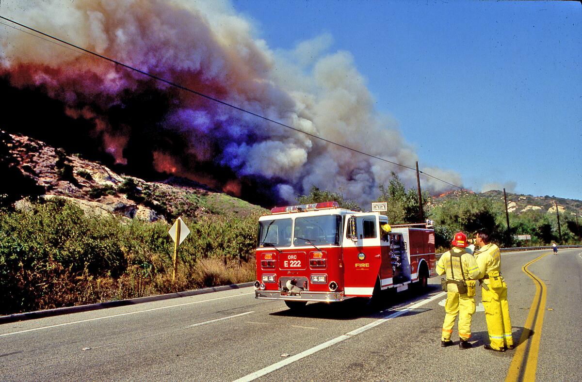 Orange County firefighters from Station 222 make a plan as flames run-up Laguna Canyon Road in October 1993.