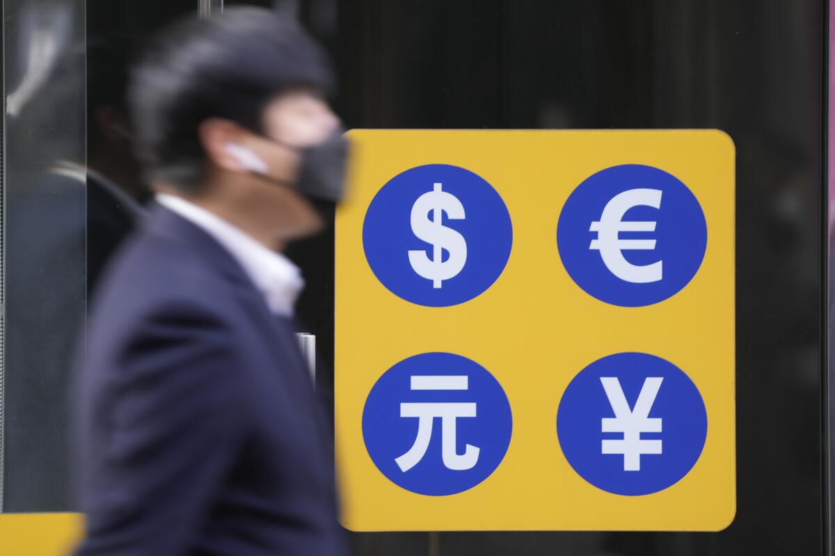 A man wearing a face mask walks near a money exchange office.
