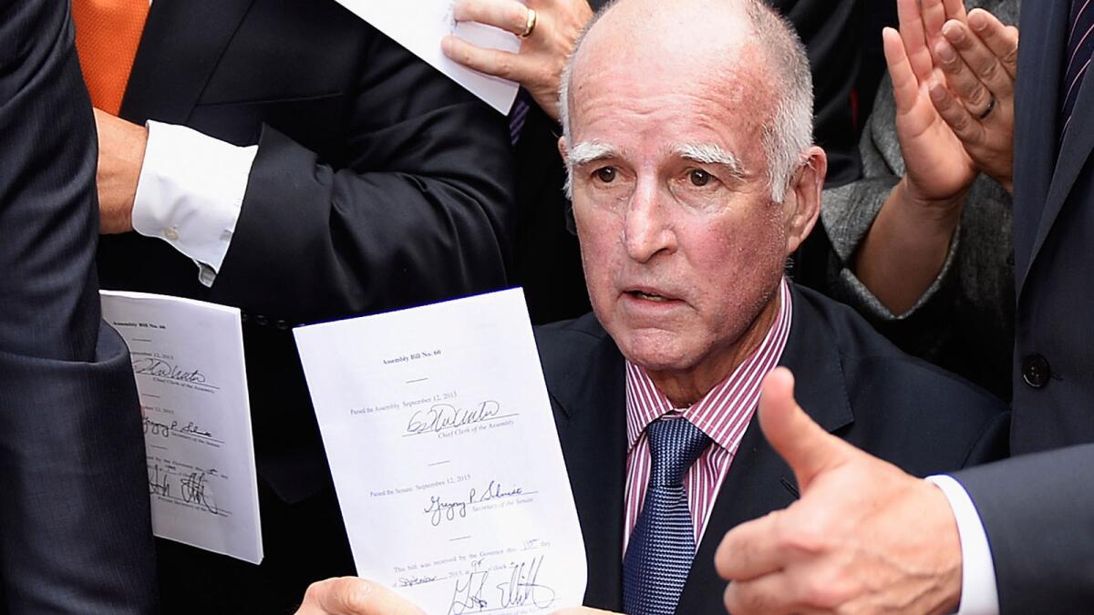 California Gov. Jerry Brown celebrates after signing bill AB60 on the steps of Los Angeles City Hall in 2013. The bill allows immigrants in the country illegally to get driver's licenses.