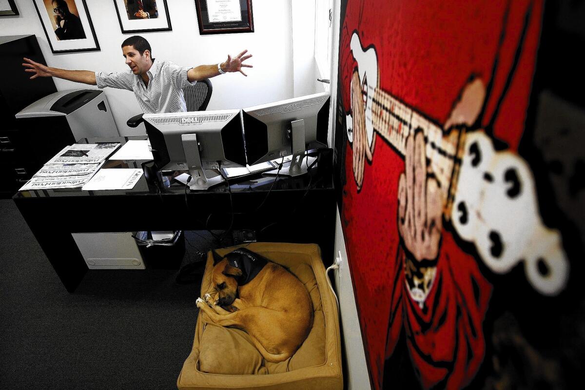 As his dog Molly sleeps nearby, Alan Smolinisky, owner of the Palisadian-Post, works at his desk at the community newspaper's new office in Pacific Palisades. Through layoffs and retirements, most of the staff Smolinisky inherited is gone, and he has raised the subscription price to $65 from $49.