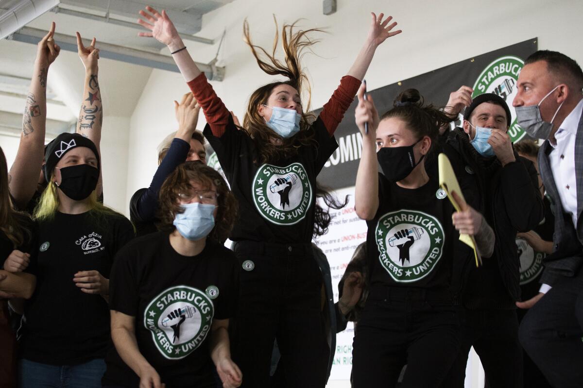 People wearing shirts that say "Starbucks workers united" jump and cheer