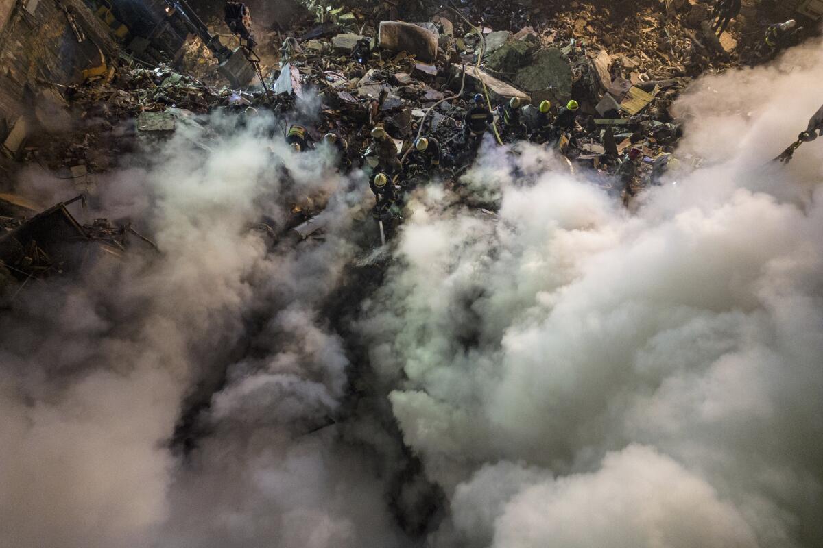 Emergency workers amid the rubble of an smoke-covered apartment building struck by a Russian missile.