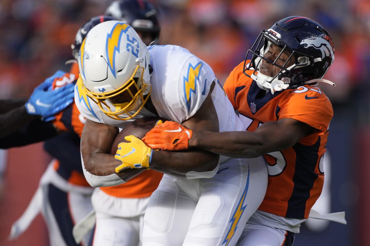 Chargers running back Joshua Kelley is hit by Denver Broncos cornerback Ja'Quan McMillian during the first half.