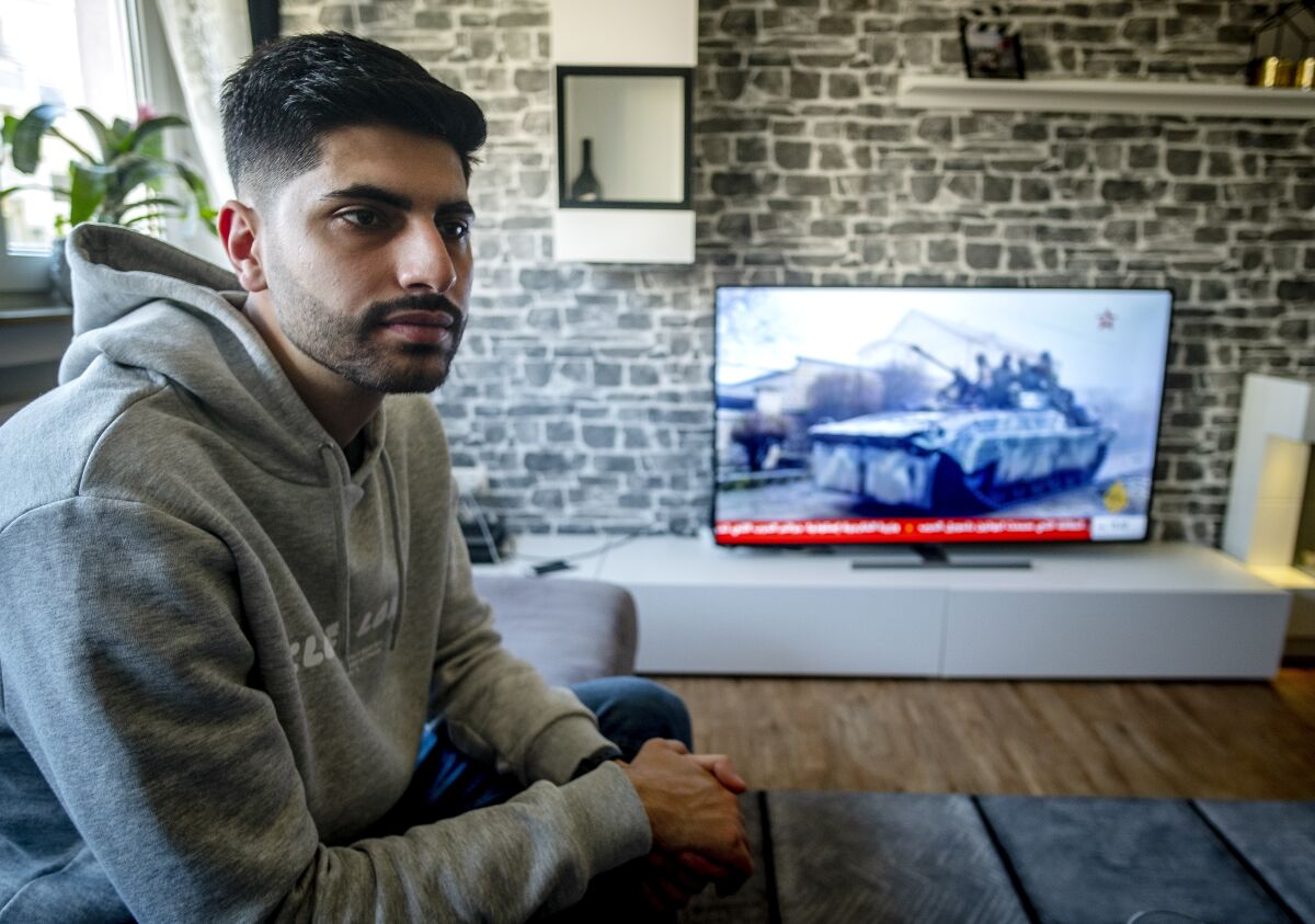 Orwa Staif, a Syrian student in the city of Kharkiv, sits on the sofa in the apartment of his parents in Nuremberg, Germany, Thursday, March 3, 2022. When Russia launched its war on Ukraine, Staif joined the exodus of people fleeing the onslaught. (AP Photo/Michael Probst)