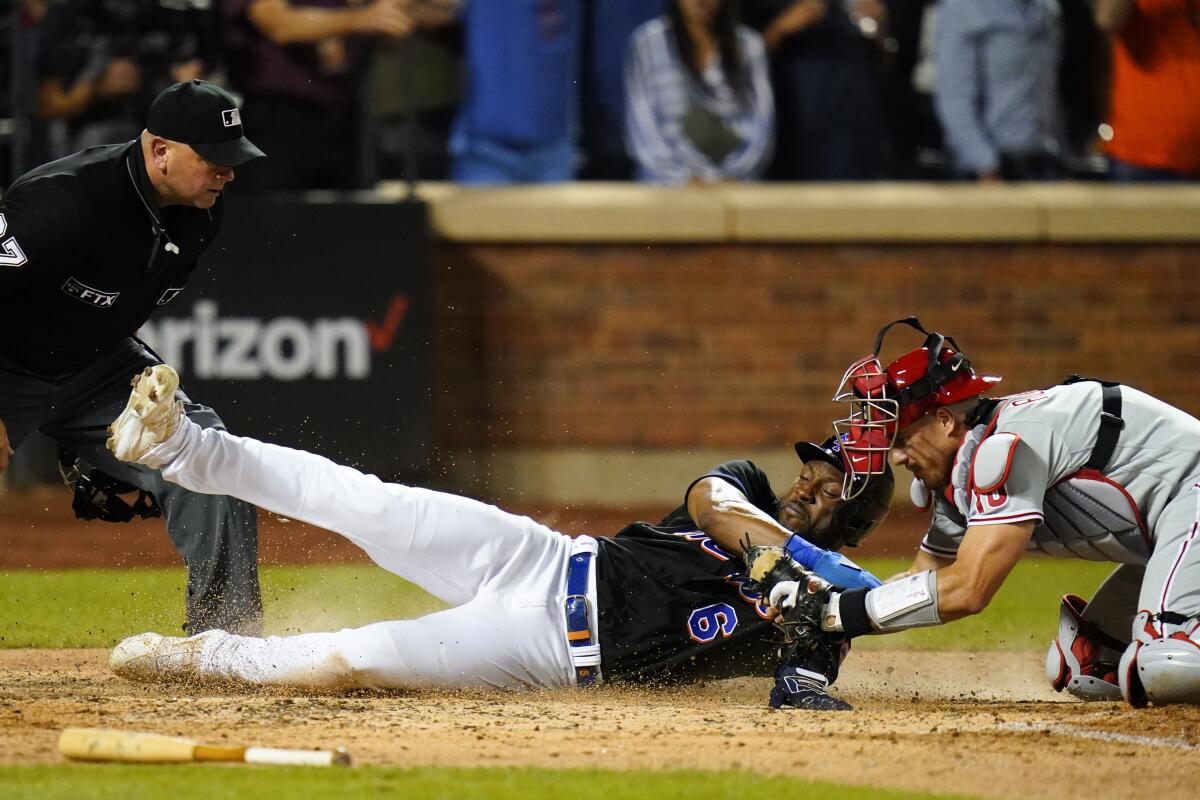 Philadelphia Phillies catcher J.T. Realmuto, right, tags out New York Mets' Starling Marte at home plate to end the ninth inning of a baseball game Friday, Aug. 12, 2022, in New York. (AP Photo/Frank Franklin II)