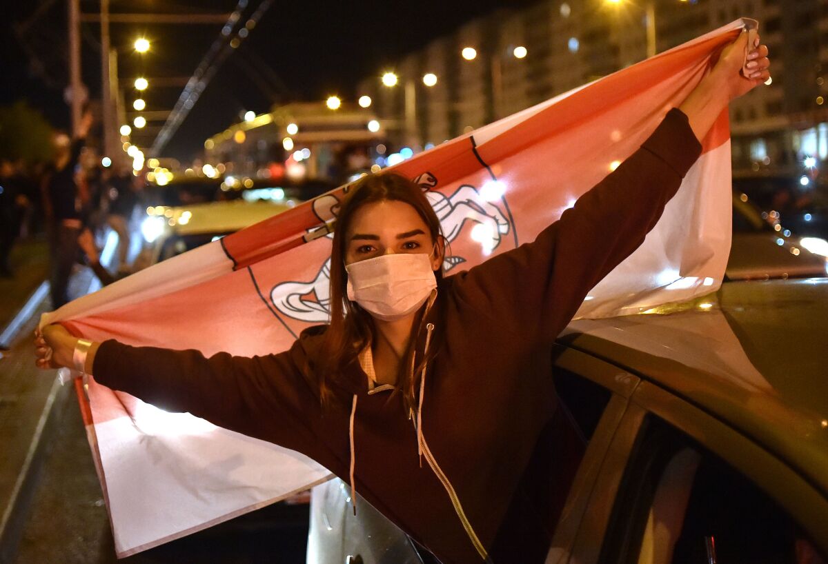 A woman holds Belarus' former flag during a protest Thursday against police violence in Minsk, Belarus.