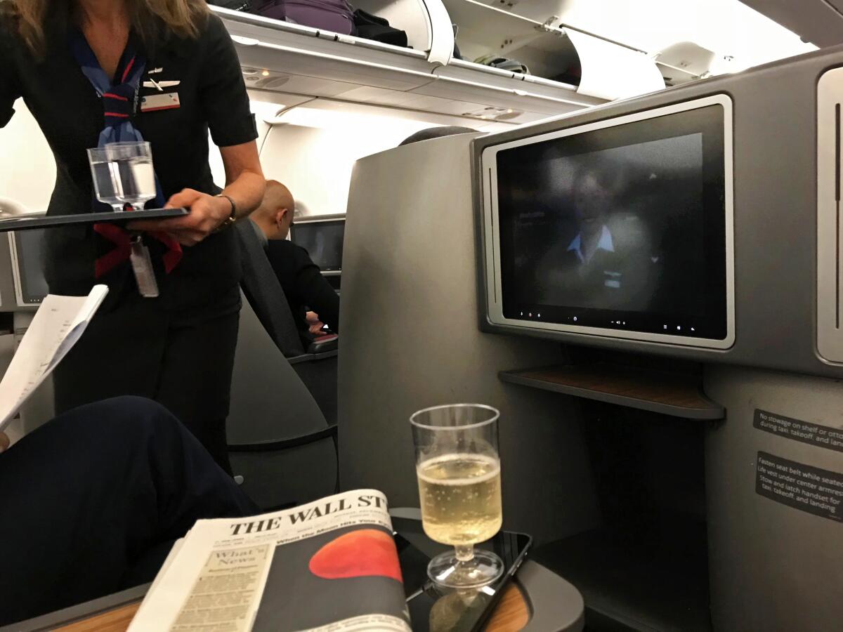 A flight attendant serves a business-class passenger. 