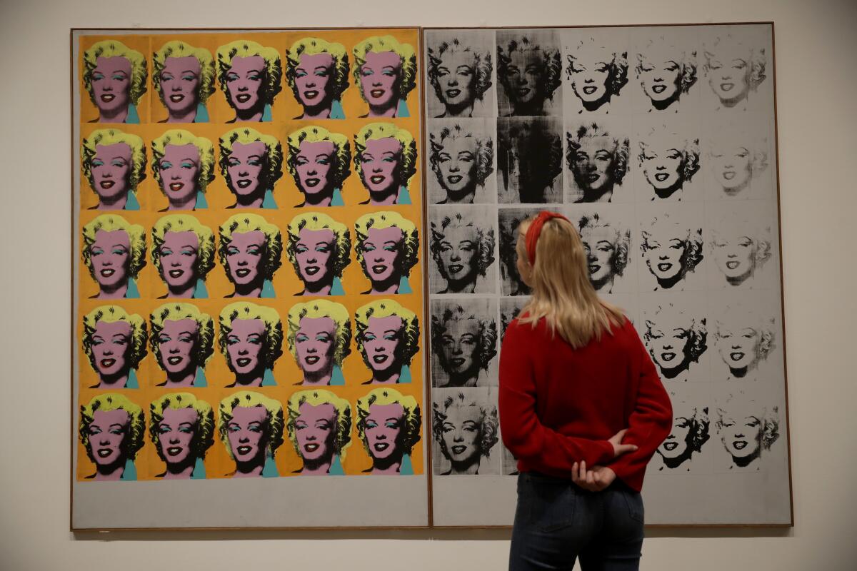 Una representante del Tate Modern, en el centro, posa junto a la obra de Andy Warhol de 1962 "Marilyn Diptych" durante una presentación a la prensa de la exposición "Andy Warhol" en el museo en Londres, el martes 10 de marzo del 2020. La muestra estará abierta al público desde el 12 de marzo hasta el 6 de septiembre. (AP Foto/Matt Dunham)