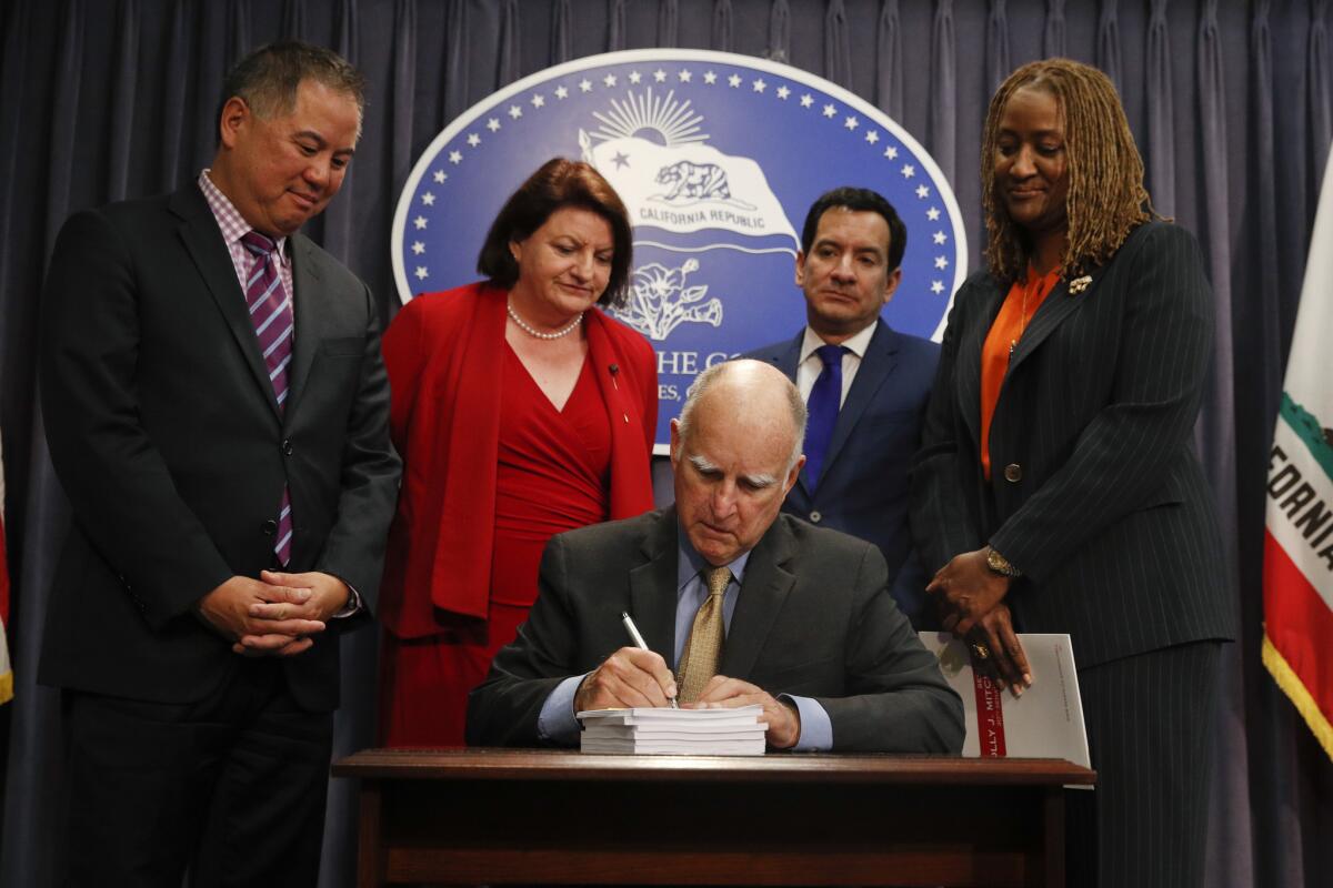 Gov. Jerry Brown signs the state budget surrounded by legislative leaders on Wednesday in Los Angeles.