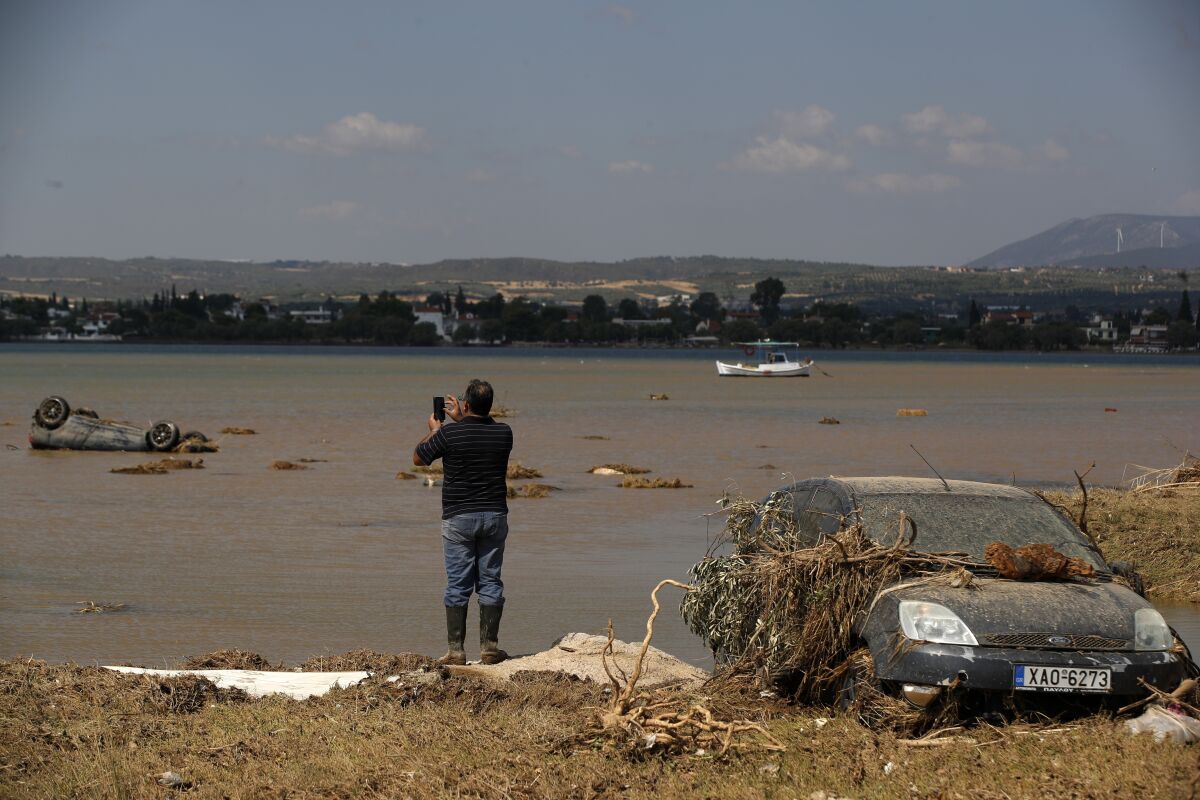 Local resident Christos Pavlou takes a photograph of his sunken car after a storm at the village of Bourtzi, on Evia island, northeast of Athens, on Monday, Aug. 10, 2020. Seven people, including an elderly couple and an 8-month-old baby, have been found dead as a storm hit the Greek island of Evia, authorities said Sunday. One person was still missing and dozens of others were trapped by floodwaters in their homes and cars. (AP Photo/Thanassis Stavrakis)