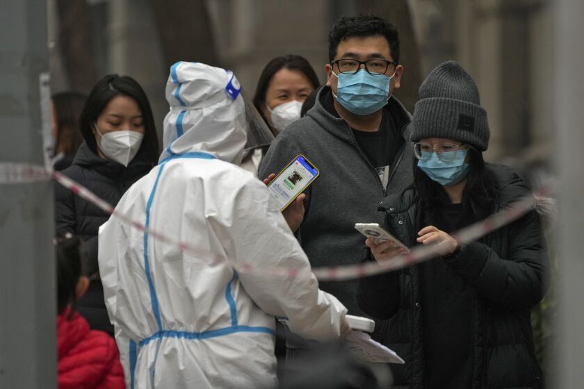 Un hombre muestra su código QR de control de salud mientras él y otras personas hacen fila para hacerse pruebas de rutina de COVID-19 en Beijing, China, el 24 de noviembre de 2022. (Foto AP/Andy Wong, Archivo)