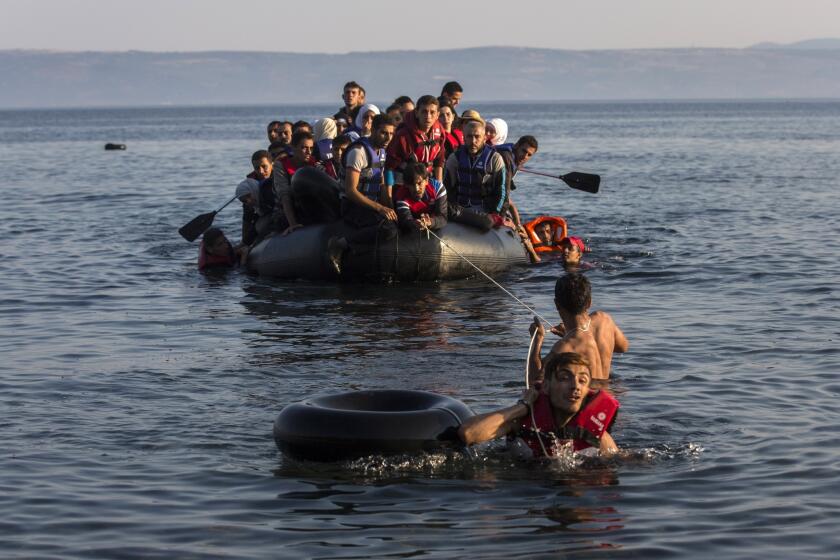 Two migrants pull an overcrowded dinghy with Syrian and Afghan refugees arriving from the Turkish coast to the Greek island of Lesbos.