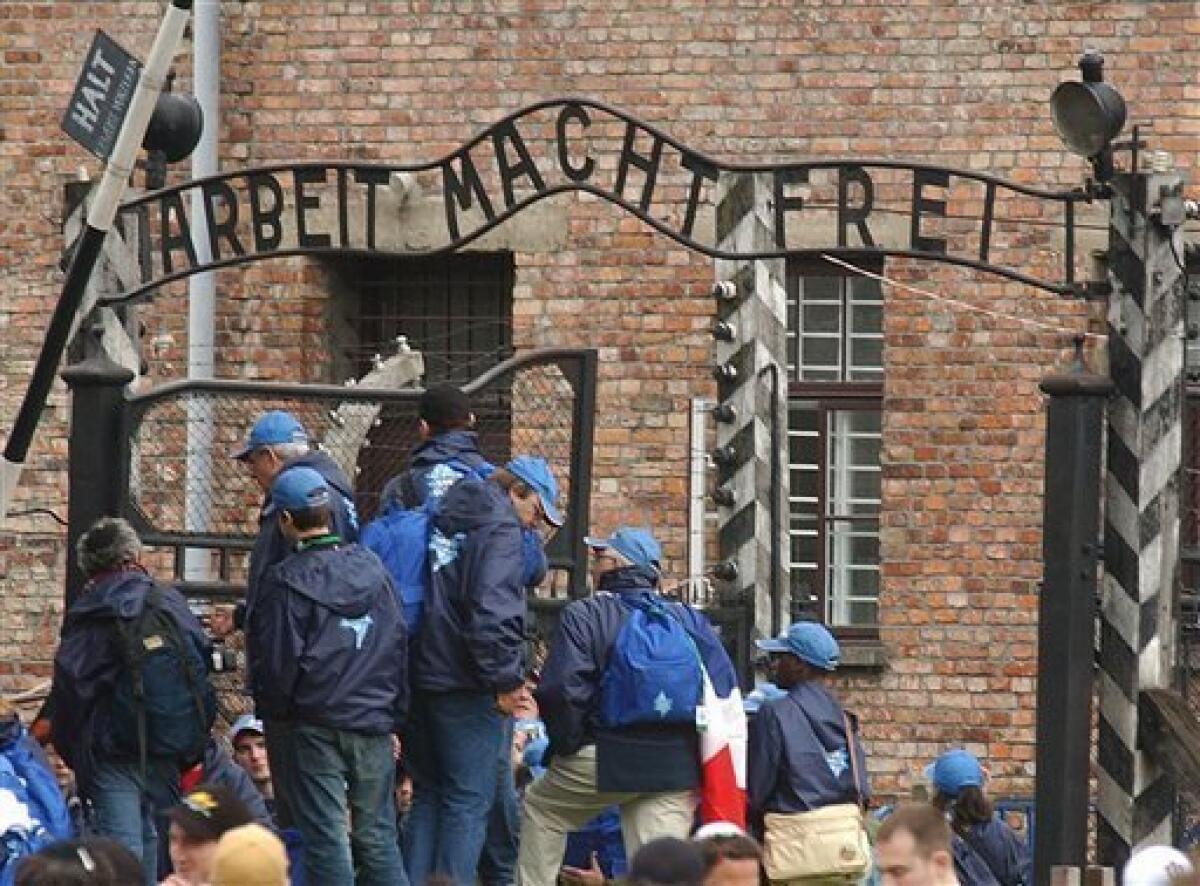 FILE - In this May 5, 2005 file photo people gather in front of the gate at the former Nazi death camp of Auschwitz, in the city of Oswiecim, Poland, just before the 18th annual March of the Living that honors some 1 million of the camp's Jewish victims who died in the Holocaust. Polish police say the infamous iron sign over the gate to the Auschwitz memorial site with the cynical phrase "Arbeit Macht Frei" _ German for "Work Sets You Free" _ has been stolen. Police spokeswoman Katarzyna Padlo said police believe it was stolen between 3:30 a.m. and 5 a.m. Friday, Dec. 18, 2009, when museum guards noticed that it was missing and alerted police. (AP Photo/Czarek Sokolowski, File)