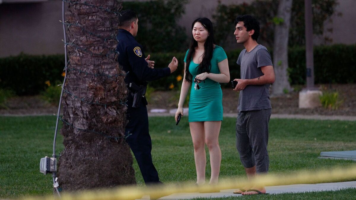 A San Diego Police Department officer stops to question a couple on Sunday, April 30, 2017 near the area in Univeristy City, San Diego, Calif. where a gunman is reported to have shot seven victims at a complex in University City.