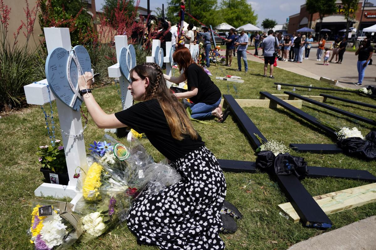 Woman signing a cross at a makeshift memorial to shooting victims