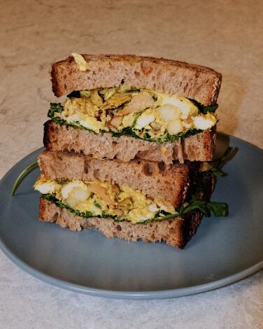 Two halves of a stacked curried chicken salad sandwich on a gray plate