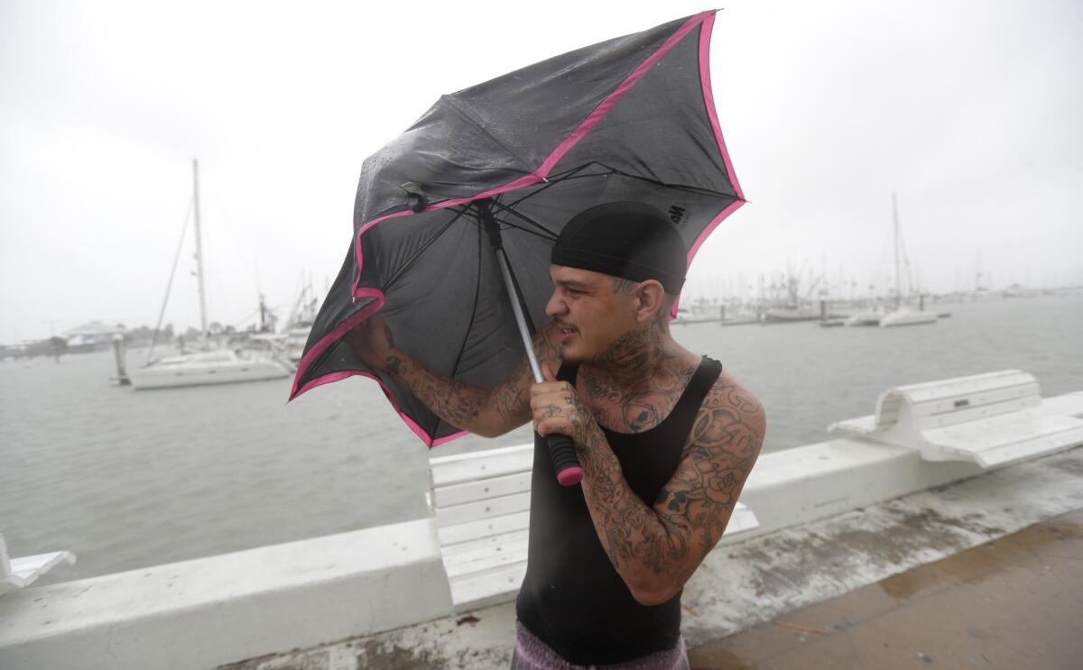 Chris Headen battles with his umbrellas as Hurricane Hanna begins to make landfall, Saturday, July 25, 2020, in Corpus Christi, Texas. The National Hurricane Center said Saturday morning that Hanna's maximum sustained winds had increased and that it was expected to make landfall Saturday afternoon or early evening. (AP Photo/Eric Gay)
