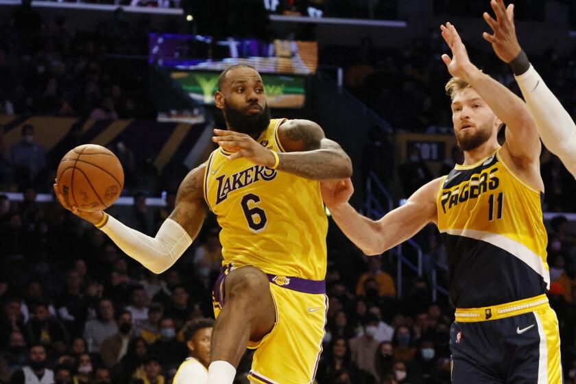 Lakers forward LeBron James leaps on the baseline to pass abasing Indiana Pacers forward Domantas Sabonis.