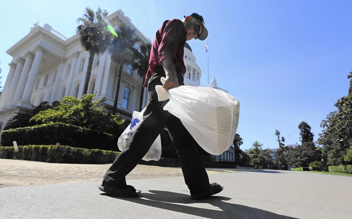 A man carries plastic single-use bags past the California Capitol in Sacramento.