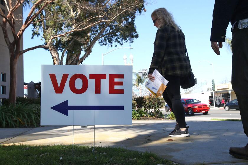 People with their paperwork, walk into the Super Tuesday Election Day center at Costa Mesa Senior Center on Tuesday.