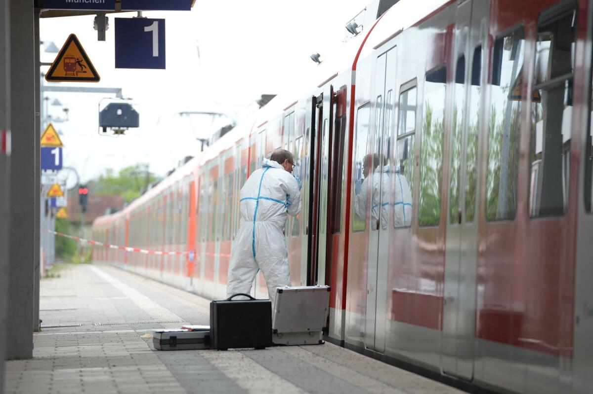 A forensic expert with the police examines a commuter train standing on a platform of the train station of Grafing near Munich, southern Germany, where a man killed one person and wounded others in a knife attack.