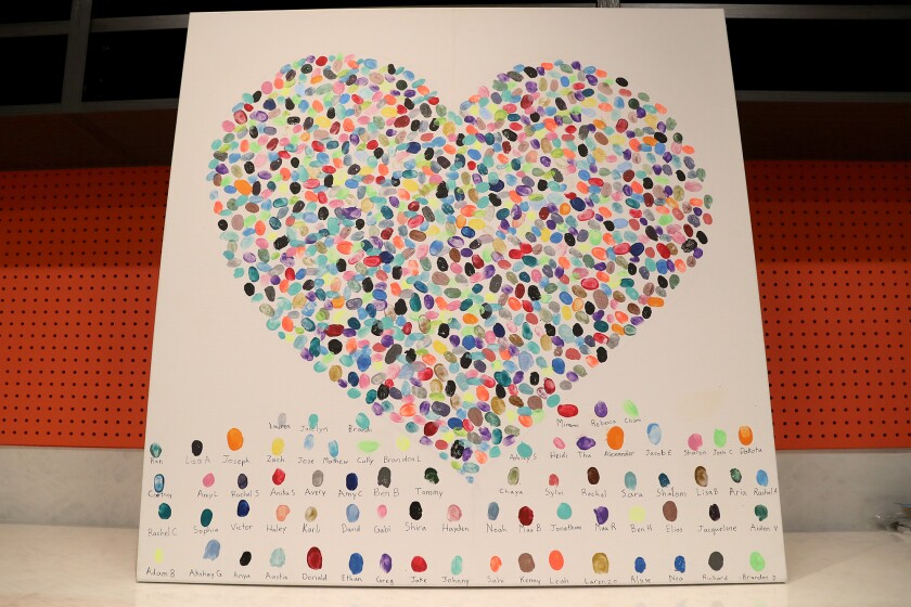 A painted heart created from the thumbprints of children is displayed in the art therapy studio.