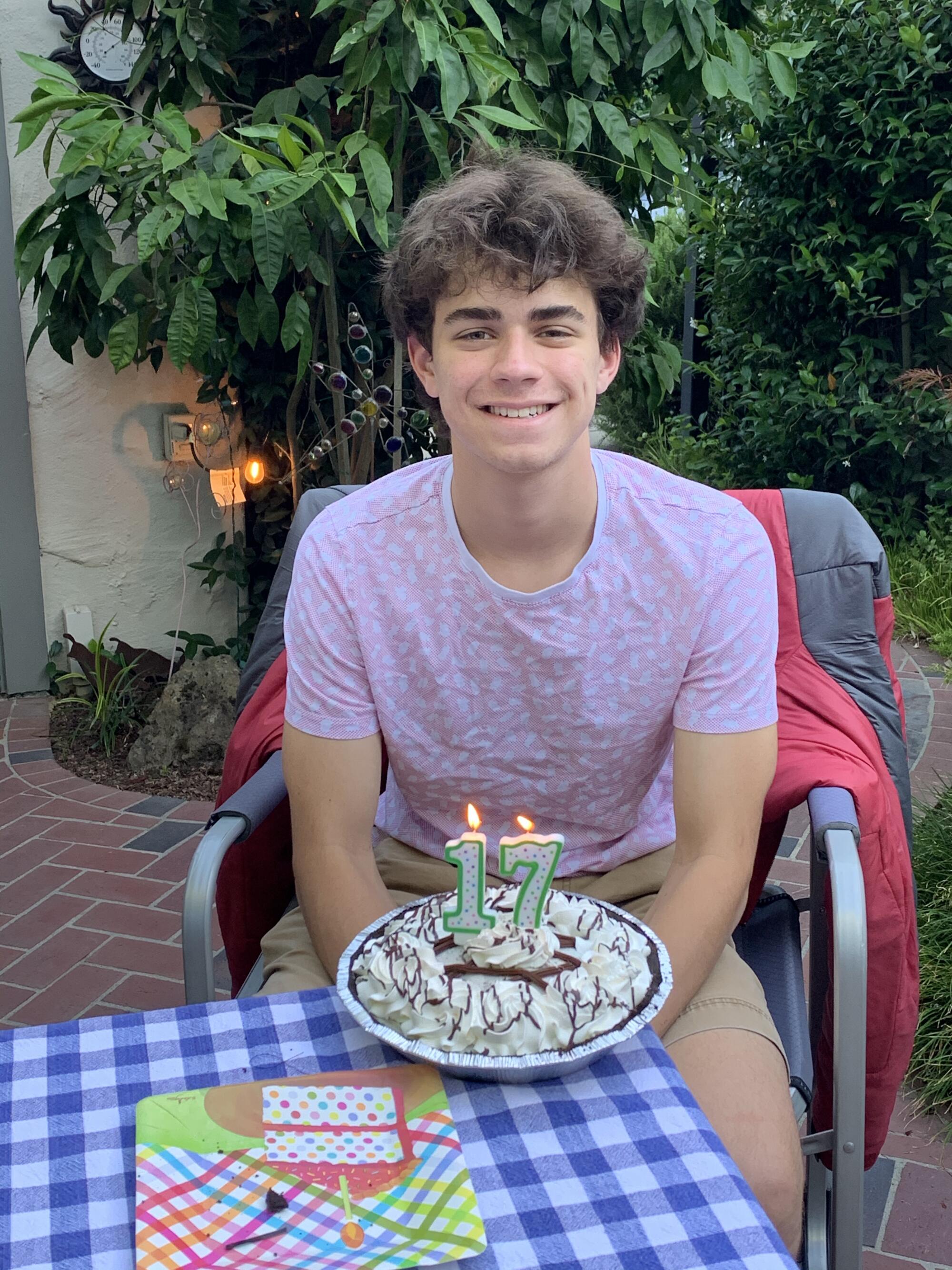 A teenager celebrating his 17th birthday with a cake and candles