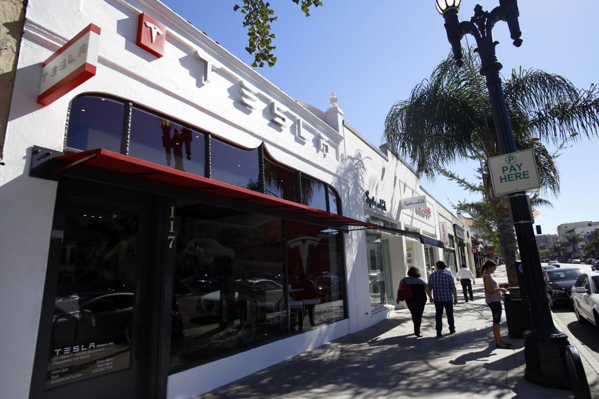 Pedestrians walk past Tesla Motors' new store in Pasadena on Aug. 29.