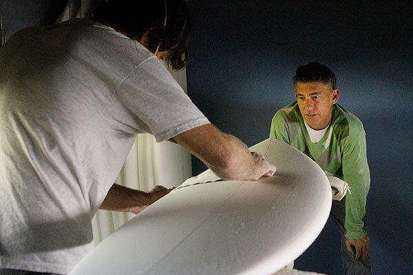 Joey Santley watches Raz Raisbeck shape a foam surfboard blank at the Lost Surfboards factory in San Clemente. The surfboard company makes some of its boards from Santley's recycled foam dust blanks. See full story