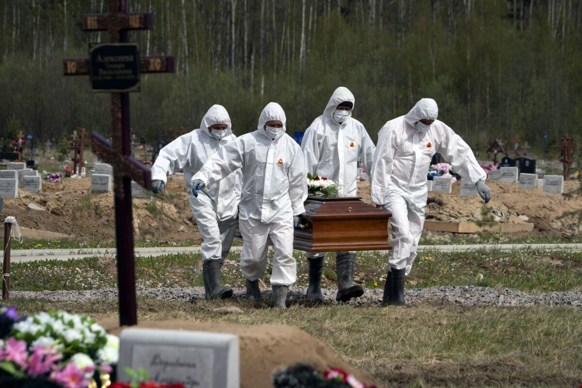 FILE - In this May 15, 2020, file photo, gravediggers in protective suits carry the coffin of a COVID-19 victim as relatives and friends stand at a distance in the section of a cemetery reserved for coronavirus victims in Kolpino, outside St. Petersburg, Russia. The head of Russia's state coronavirus task force says the number of deaths nationwide in June this year rose nearly 14 percent over June 2020. That's due to the spread of the delta variant of the virus that caused infections to soar and a record spike in deaths. Russia has suffered a surge of infections since early June, with daily new cases rising from about 9,000 in the beginning of the summer to over 23,000 in early July. For the first time in the pandemic, the daily death toll has exceeded 700, with 726 new deaths registered Friday. (AP Photo/Dmitri Lovetsky, File)