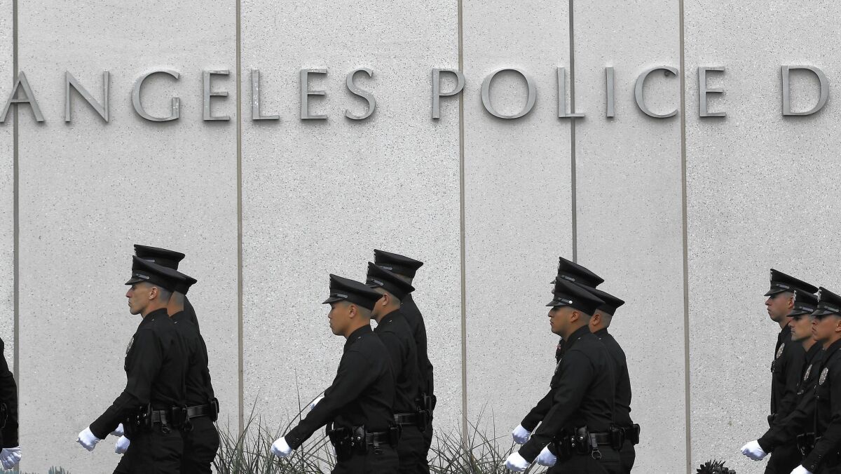 Los Angeles police officers wearing white gloves walk in file