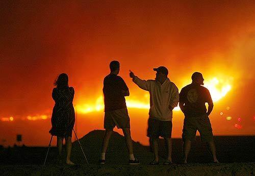 Spectators watch from Irvine Center Drive and Sand Canyon Avenue as the fire, driven by high winds, sweeps through the hills above Irvine. The fire had burned 3,800 acres in the Limestone Canyon Regional Park area.