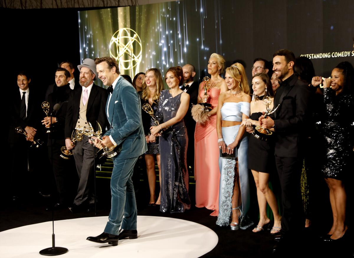 Jason Sudeikis surrounded by the rest of the "Ted Lasso" cast and crew with Emmy awards