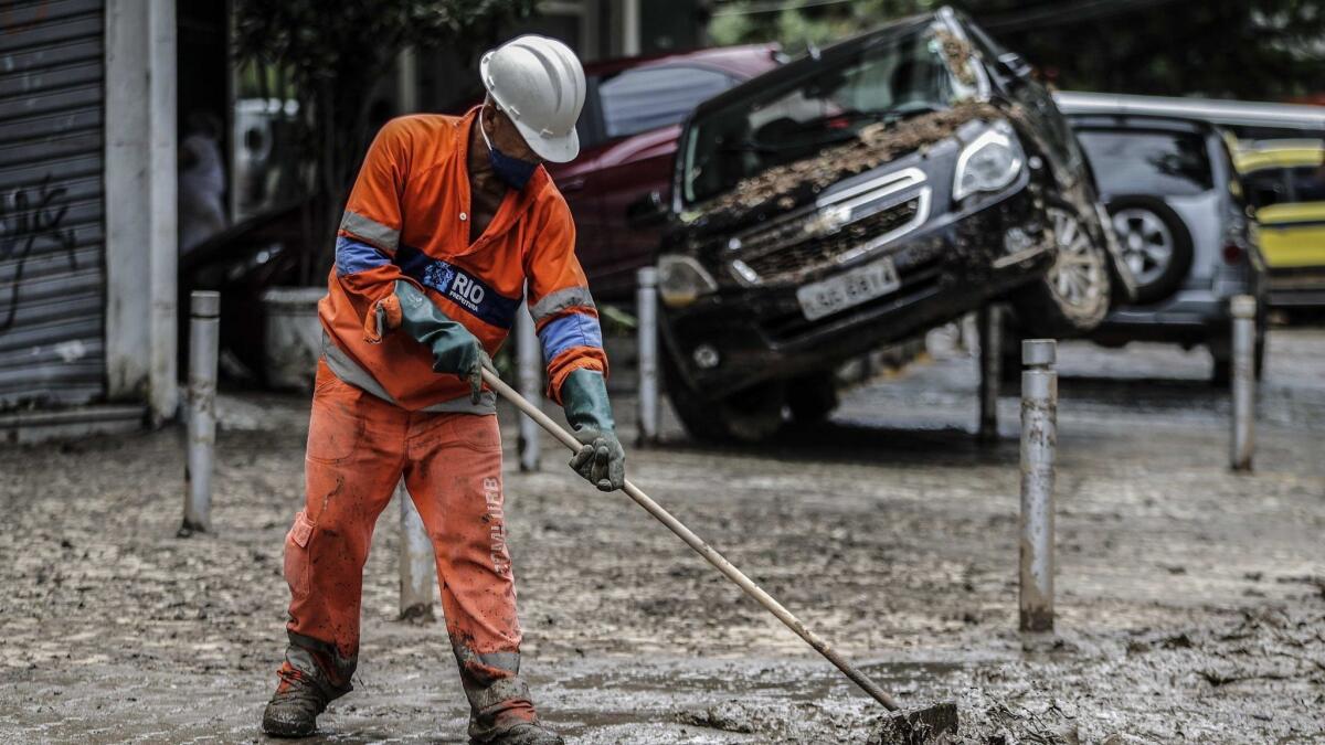 A man cleans mud from a Rio street where cars were tossed about by the storm.