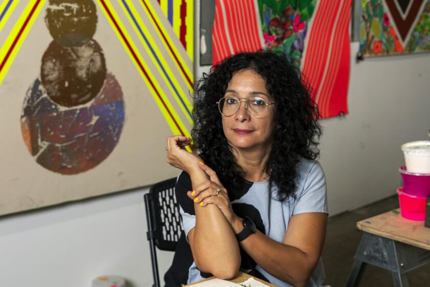 Artist Carolyn Castaño sits amid brightly patterned paintings that also employ bits of landscape in her Eastside studio