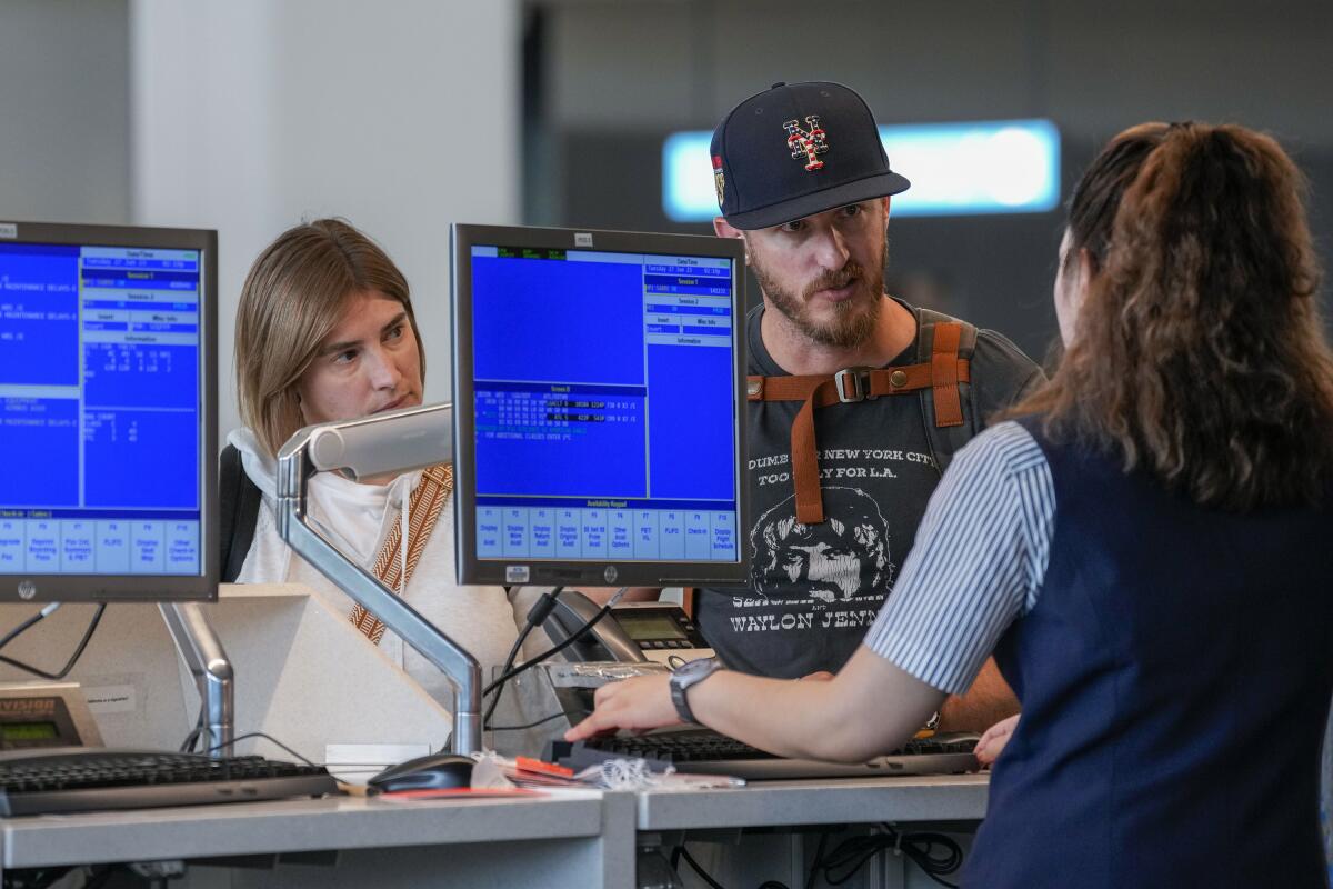 Una agente de aerolínea ayuda a pasajeros en el Aeropuerto LaGuardia de la ciudad de Nueva York