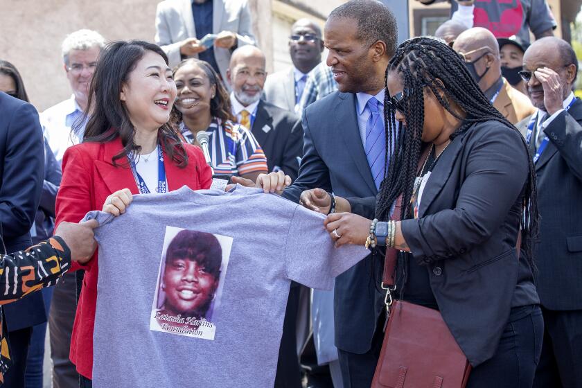 LOS ANGELES, CA-APRIL 29, 2022: Hyepin Im, left, President and Founder of Faith and Community Empowerment, receives a shirt with an image of Latasha Harlins on it from Shinese Harlins-Kilgore, cousin of Latasha Harlins, during a press conference at the intersection of Florence Ave. and Normandie Ave in Los Angeles on the 30th anniversary of the L.A. Riots. (Mel Melcon / Los Angeles Times)