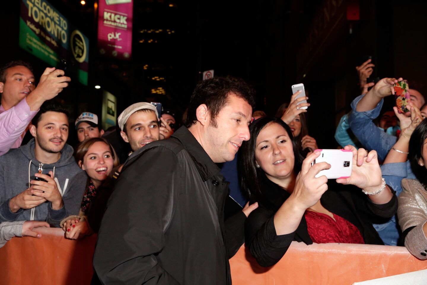 Actor and producer Adam Sandler lets a fan take a photo during "The Cobbler" premiere at the 2014 Toronto International Film Festival on Sept. 11.