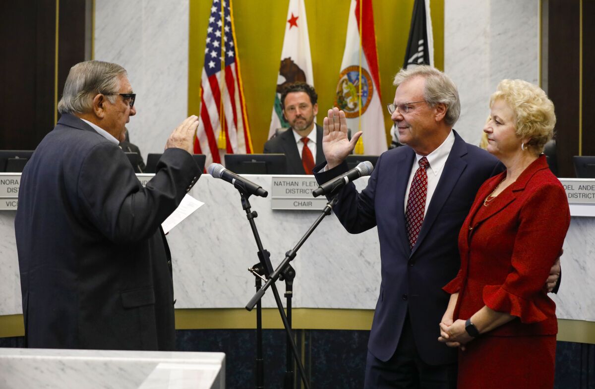 A man raises his hands to take an oath of office.