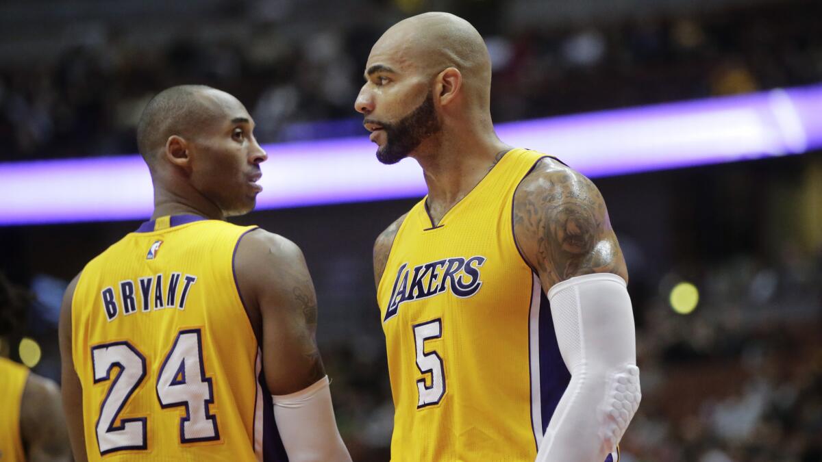 Lakers star Kobe Bryant, left, talks to power forward Carlos Boozer during the second half of an exhibition game against the Phoenix Suns on Tuesday.