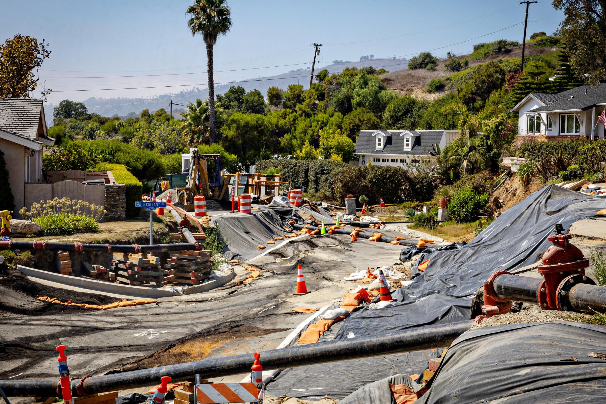 Sheets of plastic or tarp cover plots on a broken street.