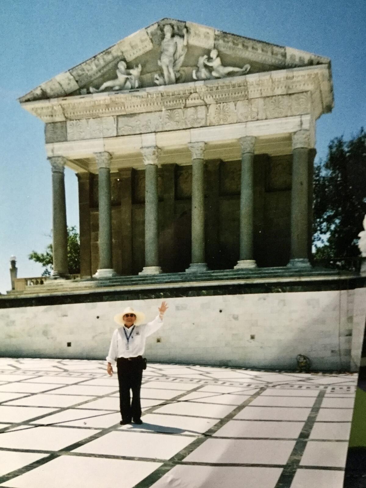 A man waves as he stands in a large, empty pool.