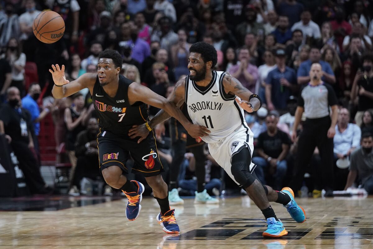 Miami Heat guard Kyle Lowry (7) and Brooklyn Nets guard Kyrie Irving (11) vie for a loose ball during the last seconds of the second half of an NBA basketball game, Saturday, Feb. 12, 2022, in Miami. (AP Photo/Wilfredo Lee)