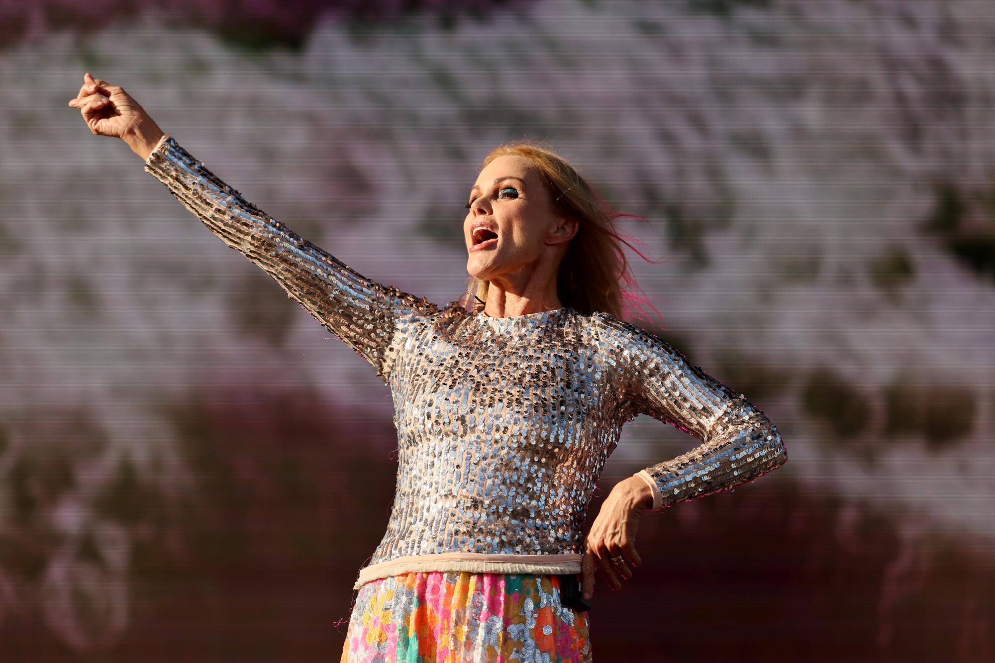 Belinda Carlisle of the Go-Go's holds 1 of her arms up.
