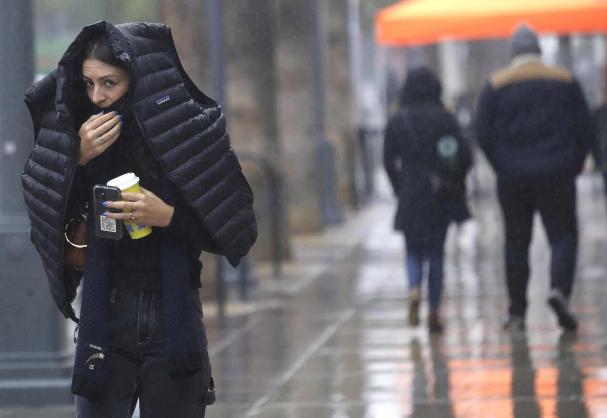 A pedestrian covers her head from the rain with her coat