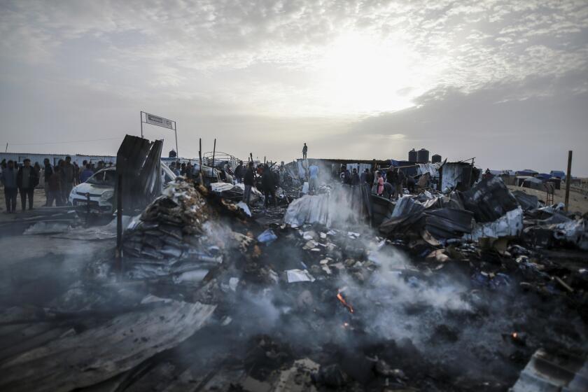 Palestinos observan la destrucción tras un ataque israelí contra un campamento de personas desplazadas, el lunes 27 de mayo de 2024, en Rafah, Franja de Gaza. (AP Foto/Jehad Alshrafi)