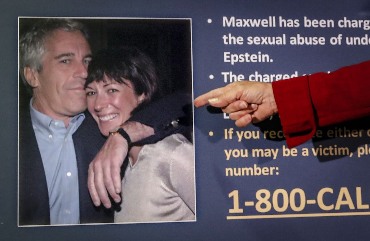 A man's hand points to a photo of Epstein and Maxwell on a poster board with details of his case