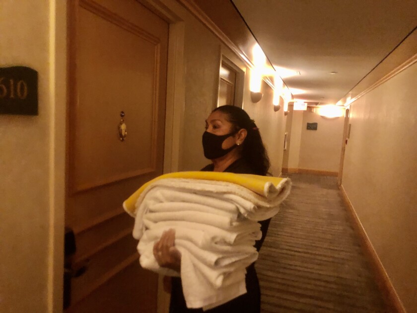 A hotel housekeeper holding a stack of white towels.