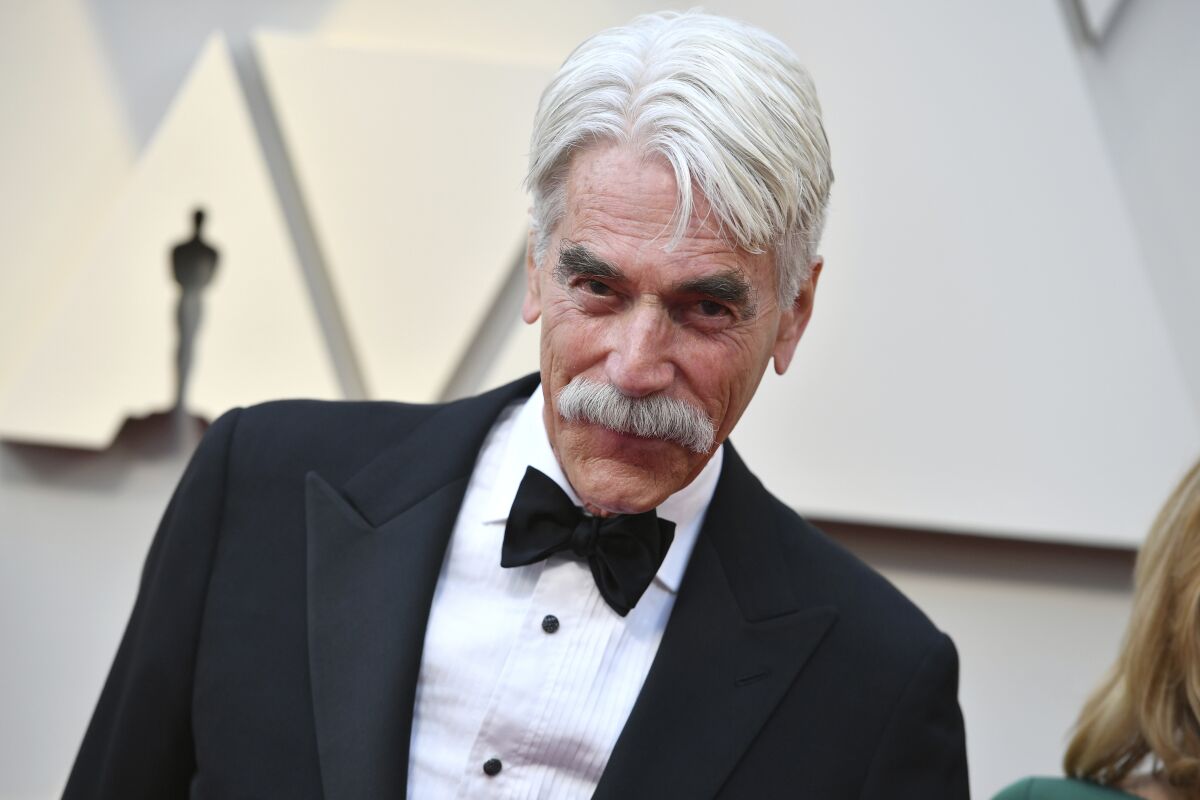 A man with white hair and a white mustache wearing a black tuxedo